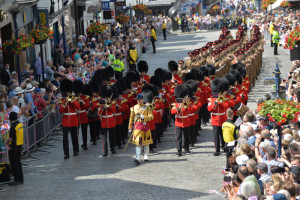 Led by the Band of the Grenadier Guards the Armed Forces Day Parade makes its way through Guildford in front of cheering crowds. Today, thousands of people across the country celebrated the men and women of the Armed Forces, past and present, at more than 150 events to mark the seventh annual Armed Forces Day. Events ranged from large scale parades to simple community events, but the main focus of attention was at the National Event in Guildford, attended by His Royal Highnesses The Duke of York and the Prime Minister David Cameron. The Secretary of State for Defence Michael Fallon and the Worshipful Mayor of Guildford Nikki Nelson-Smith also attended. The days celebrations began with a thanksgiving service at Guildford Cathedral, followed by a parade of more than 900 Service personnel, veterans and cadets through the historic heart of Guildford from the High Street to the outdoor events arena, Stoke Park. The Duke of York took the salute on the parade route on behalf of The Queen and Royal Family, as the world famous Red Arrows roared over the square in tribute. Afternoon celebrations continued Stoke Park with a variety of military displays including a Royal Air Force GR4 Tornado flypast. Visitors also enjoyed a Sea King search and rescue demonstration, Spitfires and Hurricaines from the RAF Battle of Britain memorial Flight and a Swordfish biplane from the Royal Navy Historic Flight. In addition, crowds of an estimated 60,000 were treated to three parachute displays from the Royal Navy Raiders, the Army Red Devils and the RAF Falcons, as well as the Royal Signals White Helmet motorbike display team on the ground. The Red Arrows took to the skies again as the military celebrations drew to a close accompanied by a tri-service group of military bands made of Her Majestys Royal Marines, Portsmouth, the Band of the Grenadier Guards, and the Central Band of the Royal Air Force.