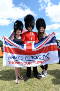 Names unknown. Two spectators with a Guardsman from the Irish Guards at the Armed Forces Day National Event in Guildford. Today, thousands of people across the country celebrated the men and women of the Armed Forces, past and present, at more than 150 events to mark the seventh annual Armed Forces Day. Events ranged from large scale parades to simple community events, but the main focus of attention was at the National Event in Guildford, attended by His Royal Highnesses The Duke of York and the Prime Minister David Cameron. The Secretary of State for Defence Michael Fallon and the Worshipful Mayor of Guildford Nikki Nelson-Smith also attended. The days celebrations began with a thanksgiving service at Guildford Cathedral, followed by a parade of more than 900 Service personnel, veterans and cadets through the historic heart of Guildford from the High Street to the outdoor events arena, Stoke Park. The Duke of York took the salute on the parade route on behalf of The Queen and Royal Family, as the world famous Red Arrows roared over the square in tribute. Afternoon celebrations continued Stoke Park with a variety of military displays including a Royal Air Force GR4 Tornado flypast. Visitors also enjoyed a Sea King search and rescue demonstration, Spitfires and Hurricaines from the RAF Battle of Britain memorial Flight and a Swordfish biplane from the Royal Navy Historic Flight. In addition, crowds of an estimated 60,000 were treated to three parachute displays from the Royal Navy Raiders, the Army Red Devils and the RAF Falcons, as well as the Royal Signals White Helmet motorbike display team on the ground. The Red Arrows took to the skies again as the military celebrations drew to a close accompanied by a tri-service group of military bands made of Her Majestys Royal Marines, Portsmouth, the Band of the Grenadier Guards, and the Central Band of the Royal Air Force.