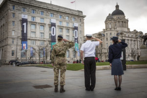 Three personnel from each Armed Force have their backs to the camera and they are saluting.