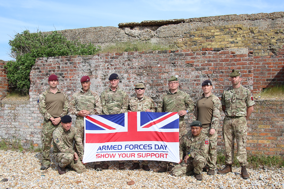 Armed Forces personnel on exercise pictured with the Armed Forces Day flag. 